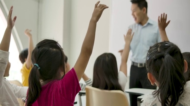 后视图的小学生举起他们的手臂上一堂课。幼儿园学前概念。