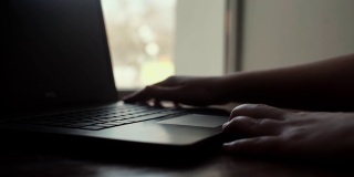 一个女人的手打开了一个笔记本电脑的盖子在窗口附近的特写慢动作