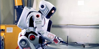 机器人焊接一个大的金属板，侧视图。工厂机器人在工作时使用焊接设备。