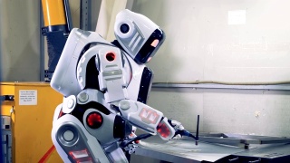 机器人焊接一个大的金属板，侧视图。工厂机器人在工作时使用焊接设备。视频素材模板下载