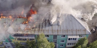 一幢高层住宅楼的屋顶起火，浓烟滚滚。俯视图