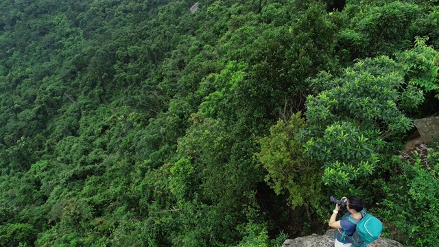 航拍的女性摄影师在热带森林徒步旅行时拍照