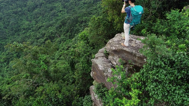 航拍的女性摄影师在热带森林徒步旅行时拍照