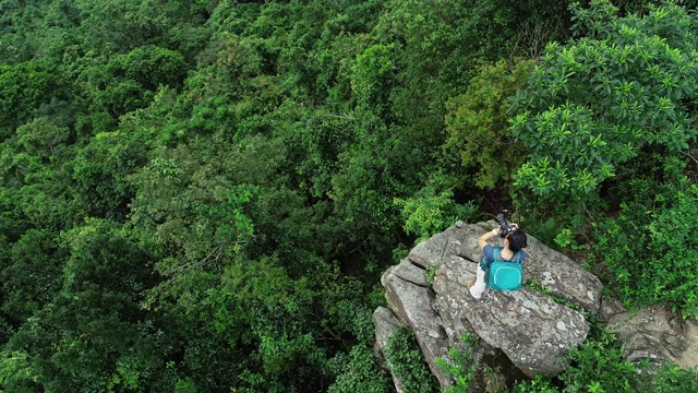航拍的女性摄影师在热带森林徒步旅行时拍照