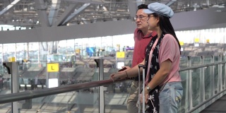 快乐的亚洲资深夫妇与行李在机场候机楼等待离开。老年人的旅程。老情人。旅行。飞行。退休了。假期有效地区分开来: