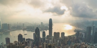 4K时间跨度宽拍摄高角度鸟瞰摩天大楼城市景观建筑行业业务金融大厦大厦和水运输物流在多云大雾的早晨日出从维多利亚峰，香港，中国。