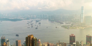 4K时间高角度的摩天大楼城市景观商业金融行业建设城市和水运物流集装箱船在多云大雾的早晨在香港太平山顶，中国。