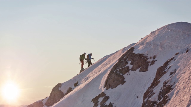 男性登山运动员在白雪覆盖的山脊上行走