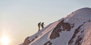 男性登山运动员在白雪覆盖的山脊上行走