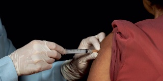 医生或护士使用注射器注射病人的上臂接种疫苗