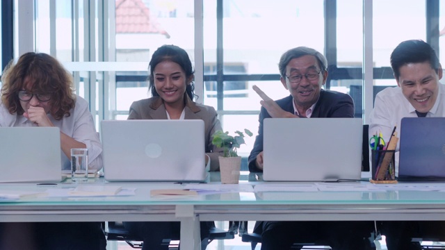 一群商业团队和高级人员看着电脑，在创业办公室庆祝他们的工作成功。业务、人员、成功,赢得的概念。人们庆祝成功，工作成功的理念。商业庆典