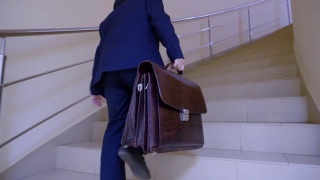 一个拿着公文包的男生正从学校走廊的楼梯上跑去上课。年轻的商人快步走上楼在大厅的商务办公室。视频素材模板下载