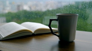 书和咖啡杯放在下雨天的木桌上视频素材模板下载
