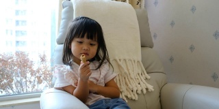 一个亚洲小女孩在家里吃零食