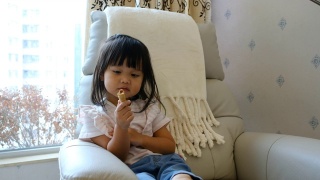 一个亚洲小女孩在家里吃零食视频素材模板下载