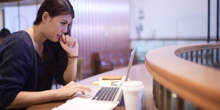 美丽的亚洲女人在电脑上工作在咖啡馆