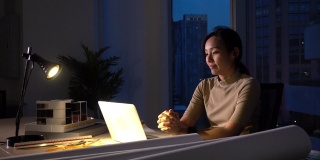 忙碌的亚洲女性晚上在黑暗的办公室工作
