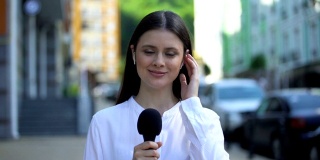 女记者戴着耳机用麦克风对着镜头讲话，现场直播每日新闻