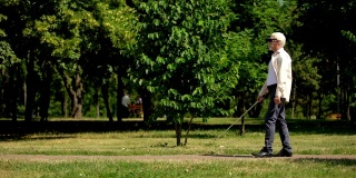盲人退休老人使用白色拐杖安全导航，在公园中独立行走