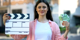 一名妇女在镜头前展示着隔板和一堆欧元，她是一名电影制作工人