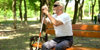 老盲人在长凳上找到长手杖，在公园里独立行走，休息