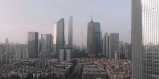 无人机的侧面飞行。在住宅区的框架，摩天大楼和广州塔。办公大楼。中国广州的日出