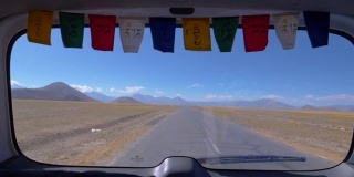 特写:透过一辆汽车的后窗，可以看到西藏一条空旷的道路。