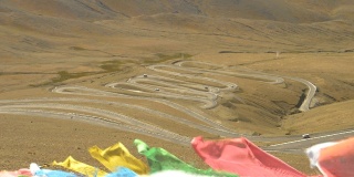 近距离观察:彩色的经幡飘扬在瓜拉山口蜿蜒的道路上