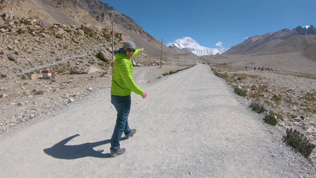 精力充沛的人指着珠穆朗玛峰的顶峰，沿着砾石小道跑下去。