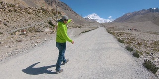 精力充沛的人指着珠穆朗玛峰的顶峰，沿着砾石小道跑下去。