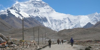 慢动作:旅行者徒步走向风吹的珠穆朗玛峰的电影镜头。