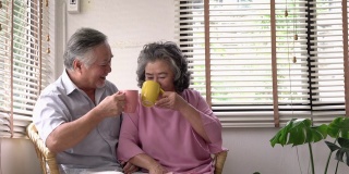 坐在家里客厅里的老男人和老女人一起送咖啡给他。夫妇老照顾退休后的生活。幸福家庭、养老之家、生活品质的理念。4 k决议。