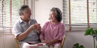 坐在家里客厅里的老男人和老女人一起送咖啡给他。夫妇老照顾退休后的生活。幸福家庭、养老之家、生活品质的理念。4 k决议。