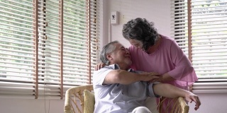 老年女性与老年男性一起在家客厅进行肩按摩。夫妇老照顾退休后的生活。幸福家庭、养老之家、生活品质的理念。4 k决议。