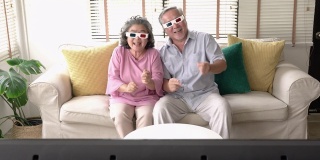 老两口在家里一起看电影激动的情绪。戴3d眼镜的老年男女。技术、娱乐和3d电影的概念。4 k决议。
