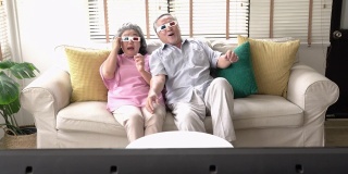老两口在家里一起看电影激动的情绪。戴3d眼镜的老年男女。技术、娱乐和3d电影的概念。4 k决议。