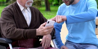 微笑的男性志愿者向残障老人讲解如何使用手机app，关爱老人