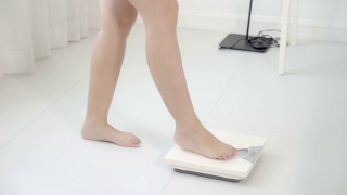 生活方式活动与腿的妇女行走测量体重秤的饮食，特写脚的女孩苗条称重测量食物控制，健康保健和幸福的概念。视频素材模板下载