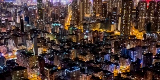 夜间，无人机在香港九龙人口密集的地区上空飞行，在孟角区有许多住宅建筑，背景是香港中部。
