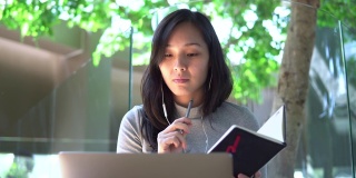 年轻的亚洲女性自由职业者使用她的笔记本电脑和工作在咖啡店