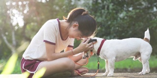 亚洲家庭十几岁的女孩玩好玩的她的宠物杰克罗素梗狗在花园在夏天的早晨