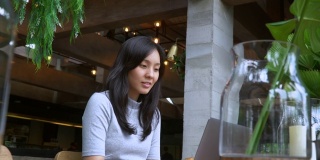 年轻的亚洲女性自由职业者使用她的笔记本电脑和工作在咖啡店