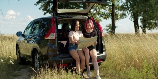 不同的女人在汽车后备箱的地图上寻找位置