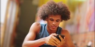 年轻帅气的黑人拿着手机。非洲男子微笑着查看智能手机
