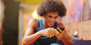 年轻的黑人男子拿着手机微笑着接受信息
