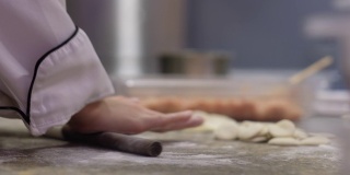 在厨房里，用擀面杖捏紧厨师的手，使面团成形。做饺子皮和馄饨皮。