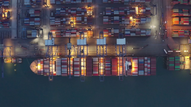 集装箱船夜间作业，远洋集装箱船经营国际进出口物流运输，鸟瞰图。