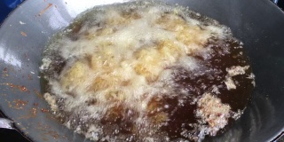 厨师正在煎鸡在锅和特写鸡在滚烫的油