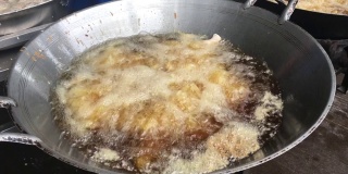 厨师正在煎鸡在锅和特写鸡在滚烫的油