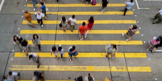 在香港孟角区，一群无法辨认的行人和汽车在黄色斑马线上行走